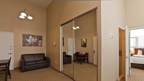 Une chambre d’hôtel avec un grand miroir, un canapé, une table à manger avec des chaises et un lit.