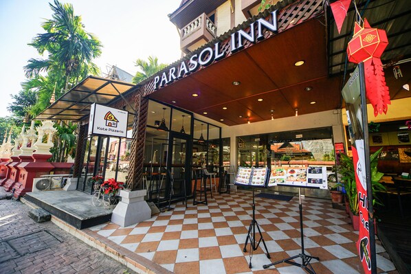 A restaurant with a checkered floor, outdoor seating, and a sign for Kate Pizzeria.