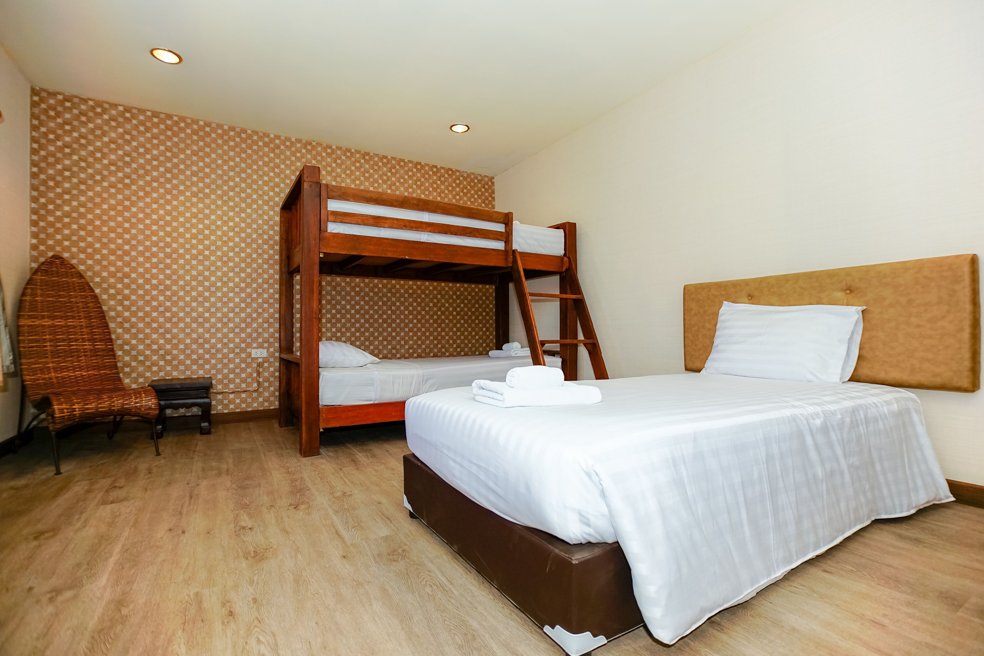 A room with two bunk beds, a small wooden chair, and a bed with a headboard.