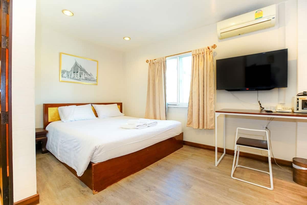 Ein Hotelzimmer mit Bett, Schreibtisch, Fernseher und einem Fenster mit Vorhängen.