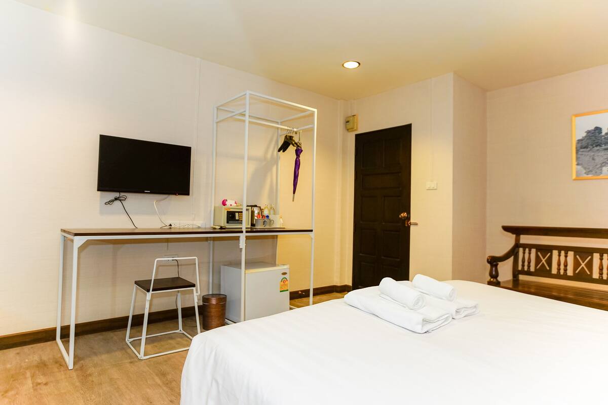 Ein Hotelzimmer mit Bett, Schreibtisch mit Stuhl, Fernseher, Kleiderschrank und einer Tür.