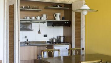 A compact kitchen with a dining area, featuring a wooden table, chairs, a sink, and a stove.
