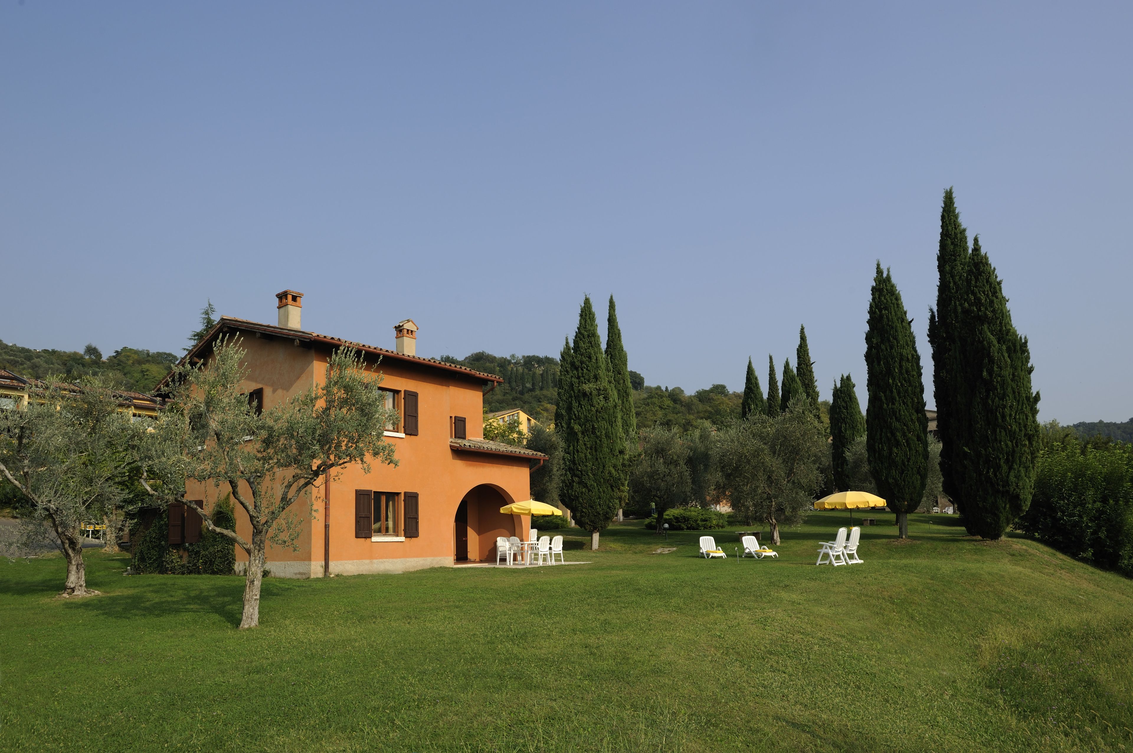 Une villa dotée d’un patio, d’un espace salon extérieur et de grands arbres.