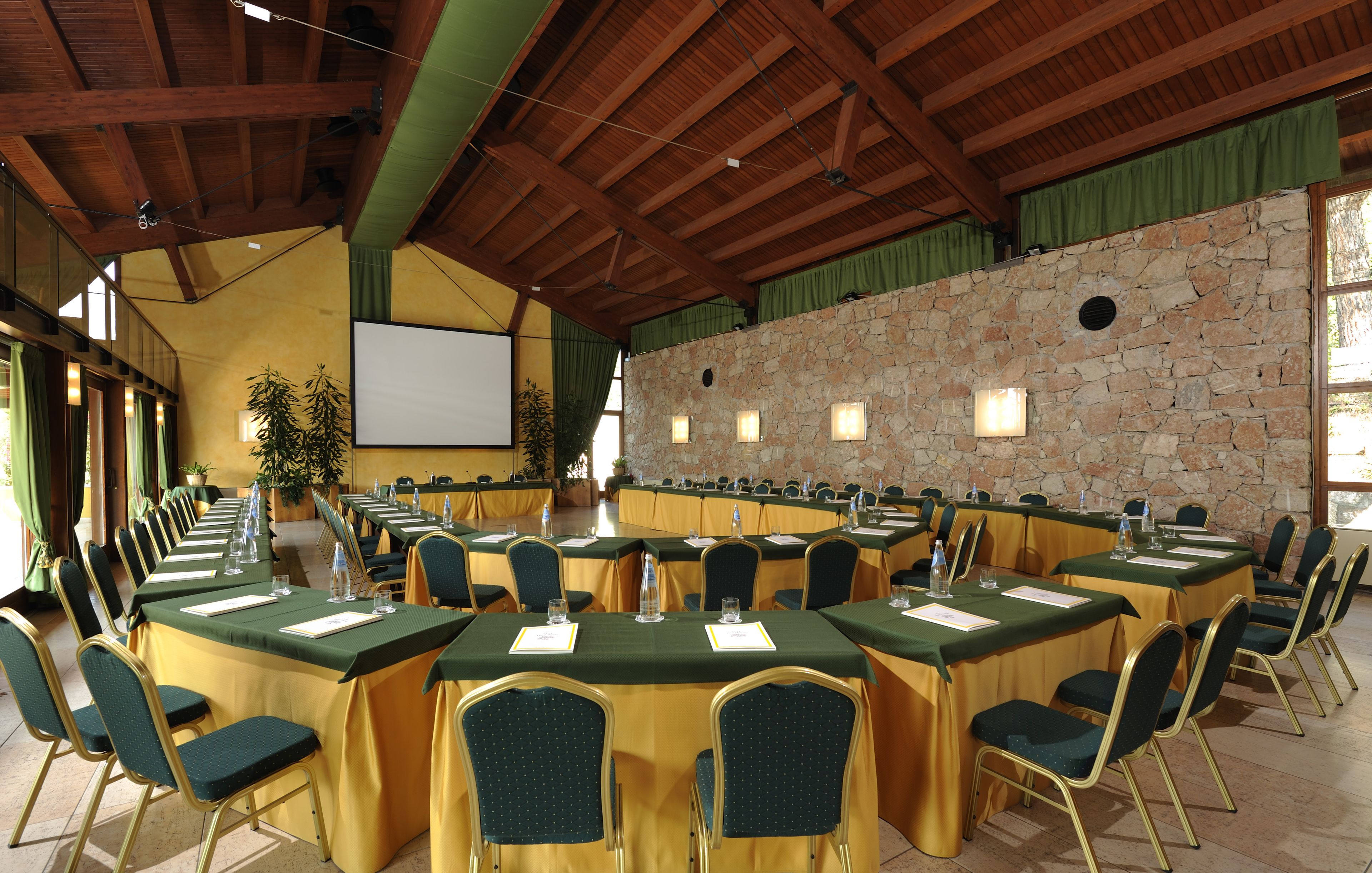 Une salle de conférence équipée de plusieurs tables, de chaises et d’un écran de projection.