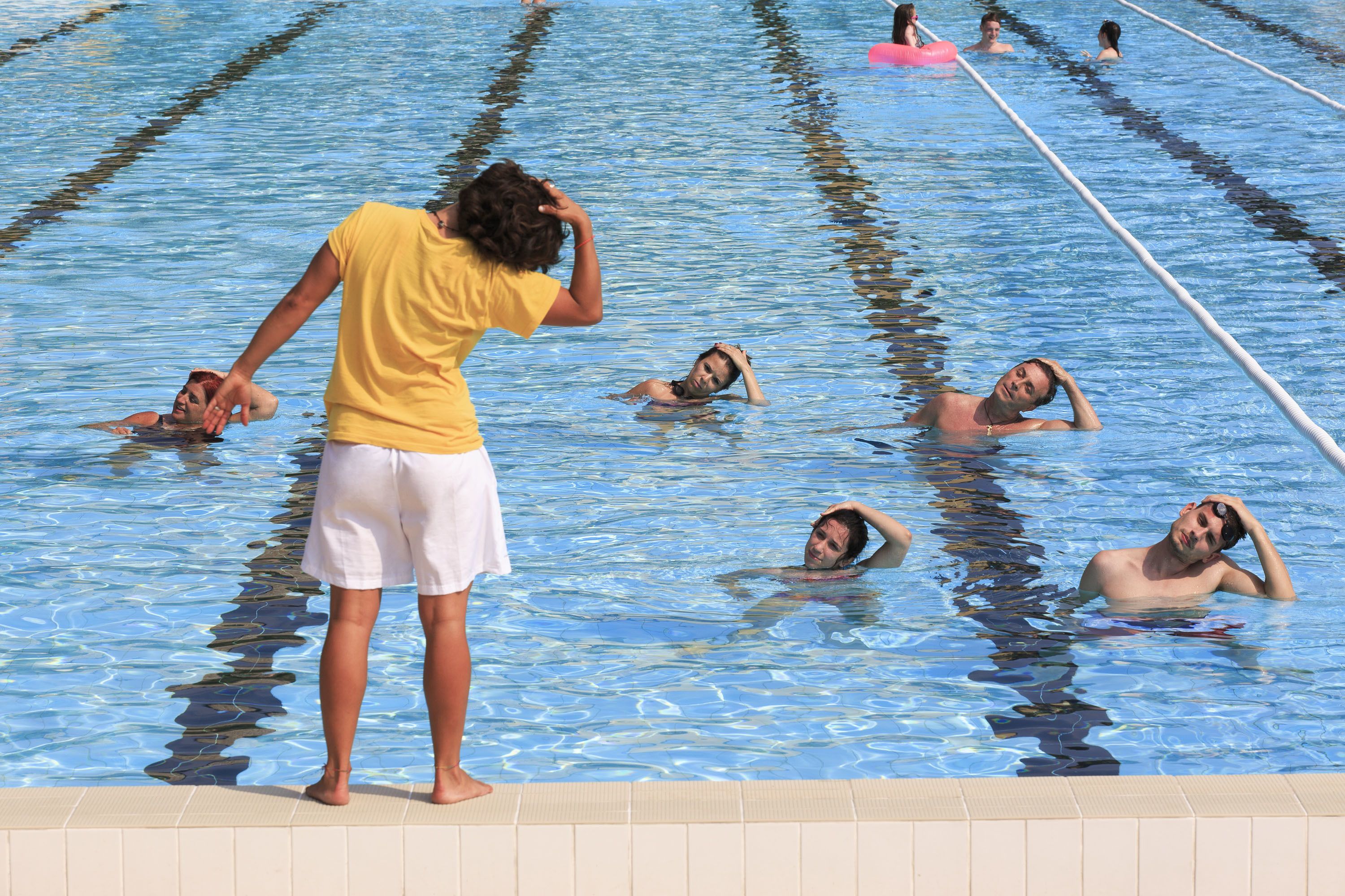 Ein Schwimmbecken mit mehreren Bahnen und darin schwimmenden Personen.