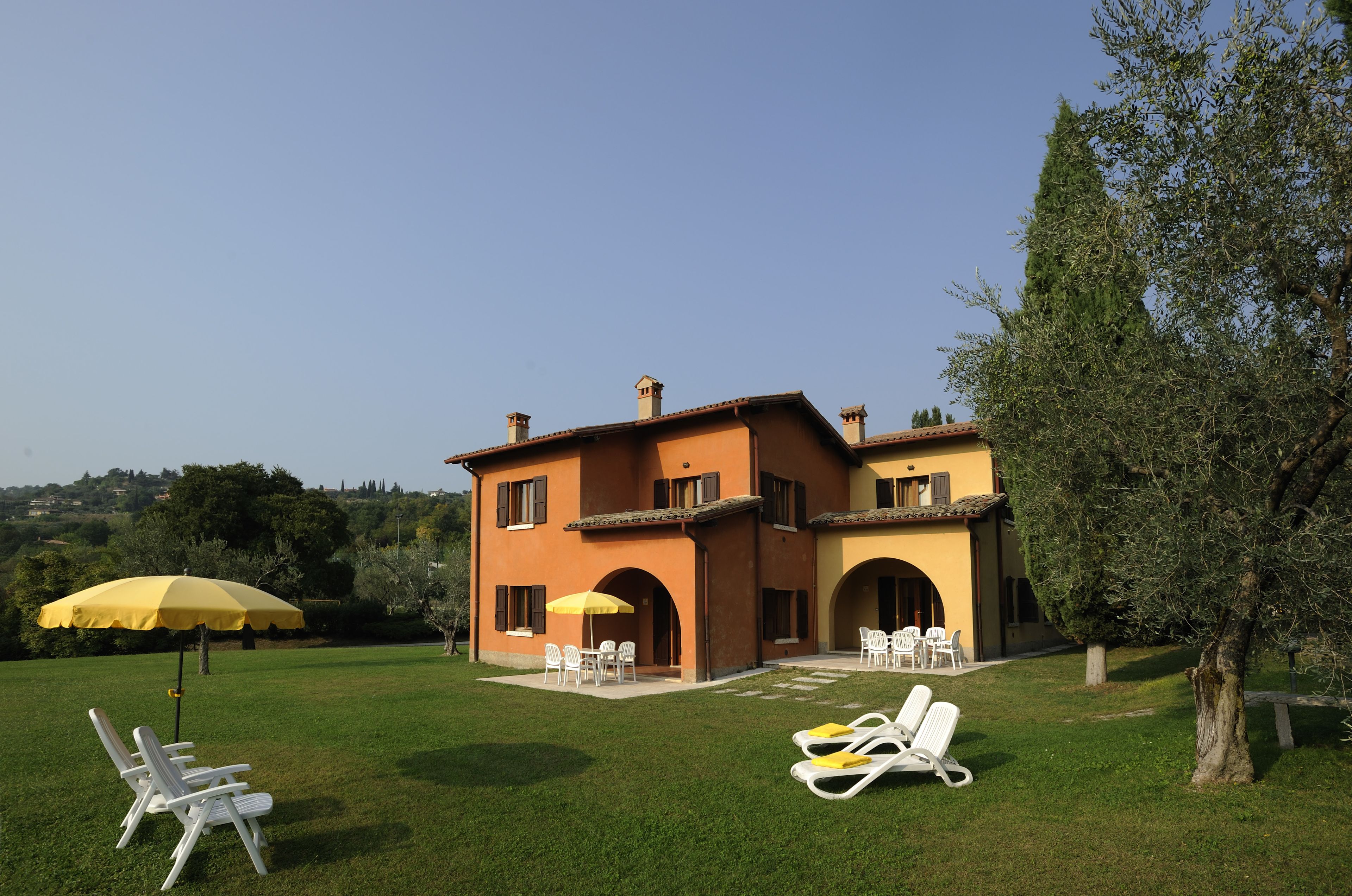 A two-story house with a patio area featuring outdoor furniture and umbrellas.