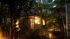 A wooden structure with a lattice design, surrounded by dense foliage and a pathway leading to it. - Amore On Buderim Luxury Rainforest Cabins (Buderim)
