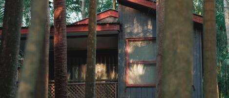 A building with a red roof, surrounded by tall trees and a wooden fence.