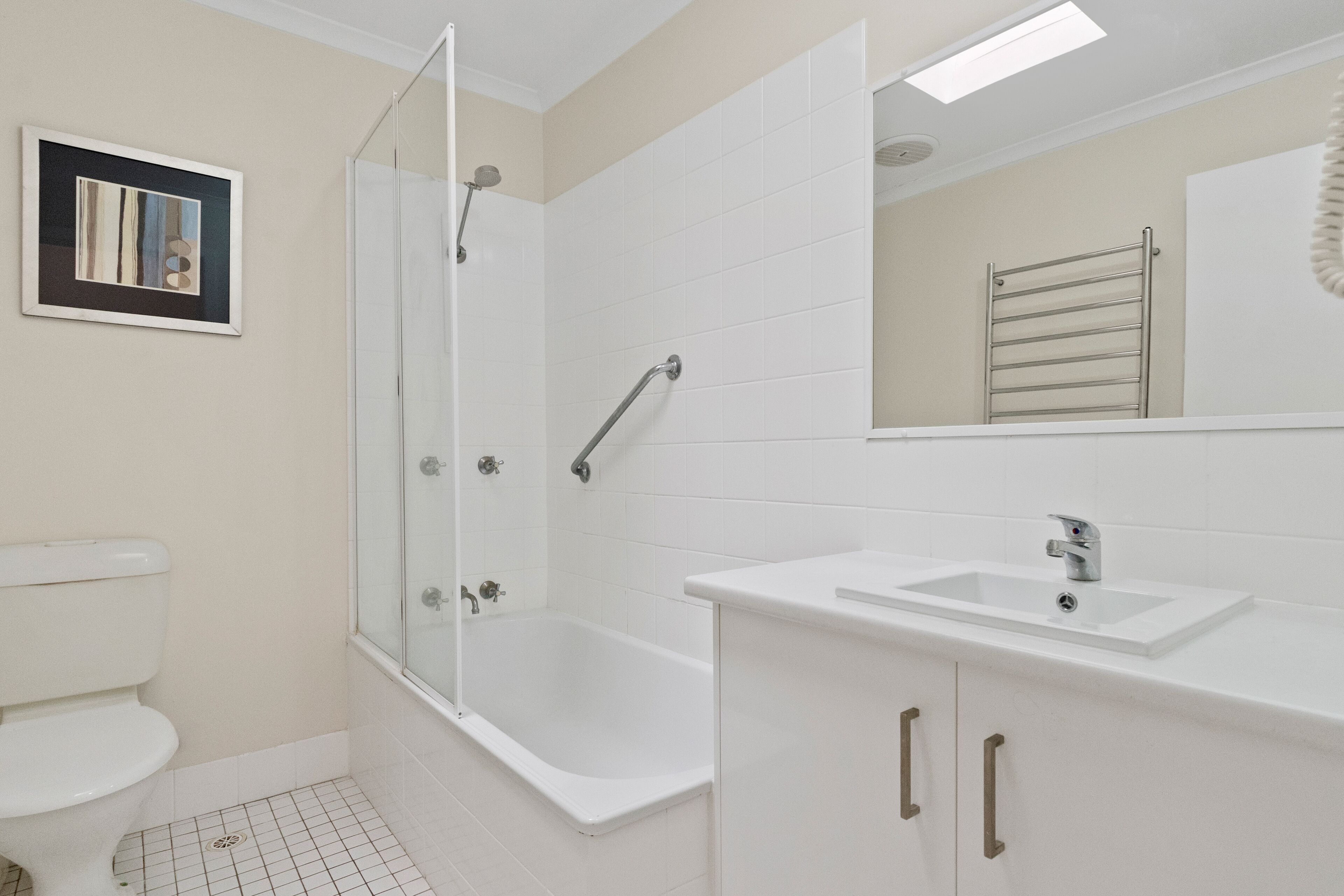 A bathroom with a glass-enclosed shower, a white sink, and a toilet.