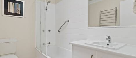 A bathroom with a glass-enclosed shower, a white sink, and a toilet.