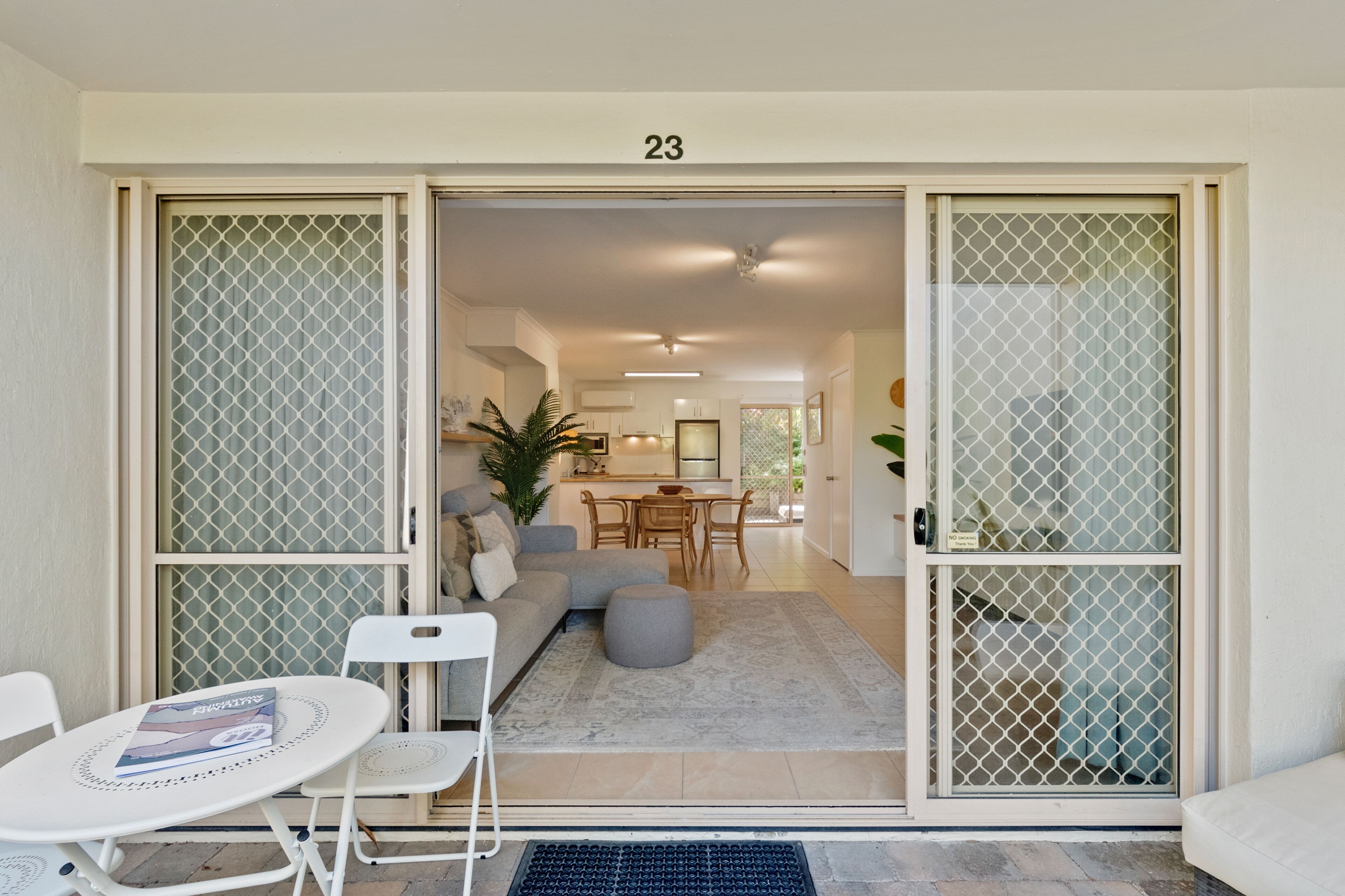 An open sliding door leading to a living area with a sofa, chairs, a small table, and a rug.