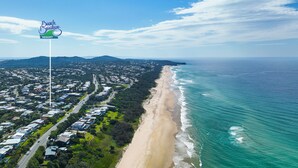 Vista aérea de una zona costera con una playa, un cartel de Beach Breakers Resort y una combinación de edificios residenciales y comerciales.