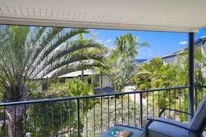 A balcony with a view of a tropical garden and a house.