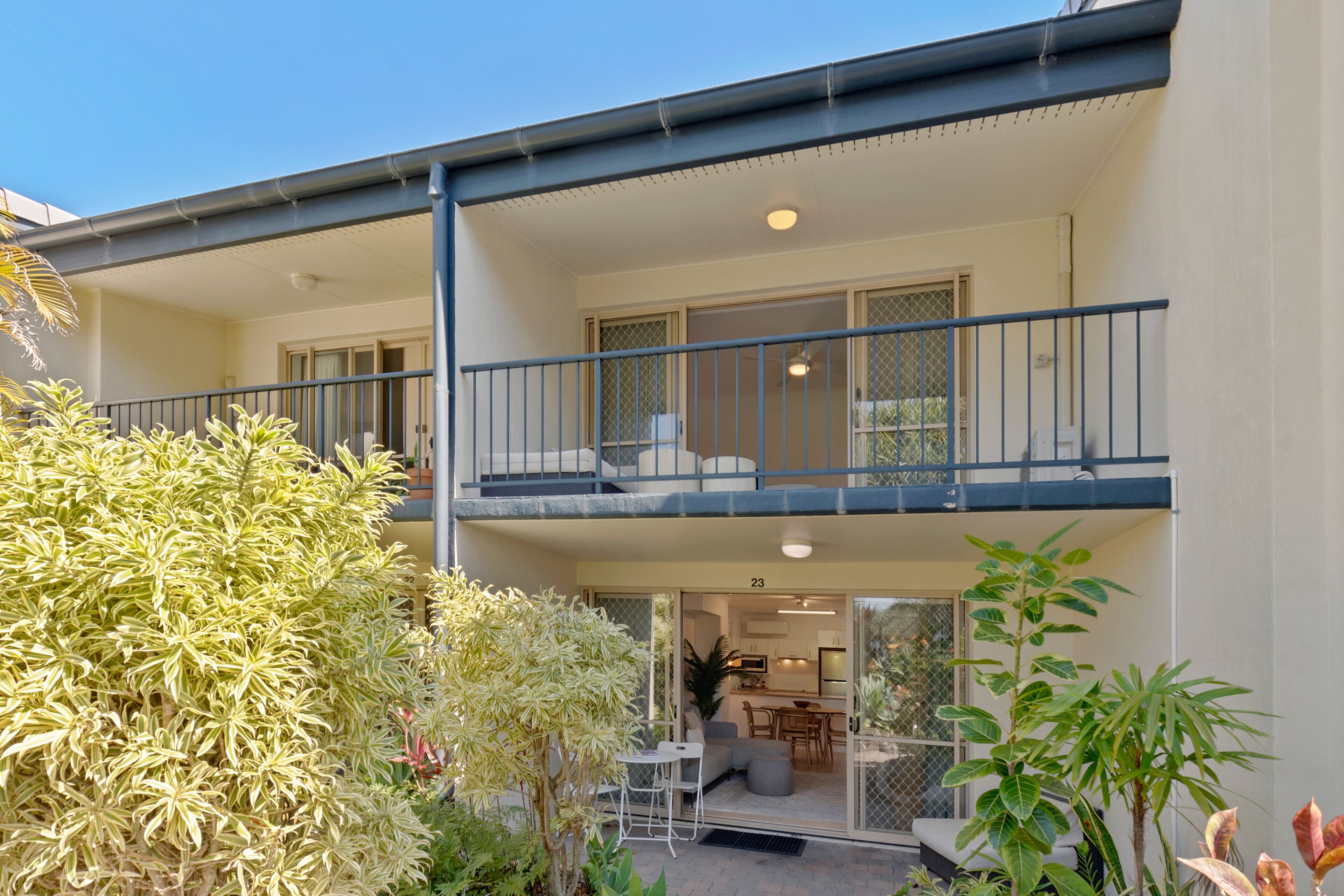 A two-story residential building with a balcony, a dining area, and a kitchen visible through the glass doors.