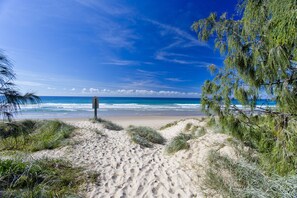 A sandy beach path leading to the ocean with sparse vegetation and a clear sky. - Sails Lifestyle Resort (Peregian Beach)