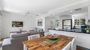 Une cuisine moderne avec des meubles blancs, une table à manger en bois et un four encastré.
