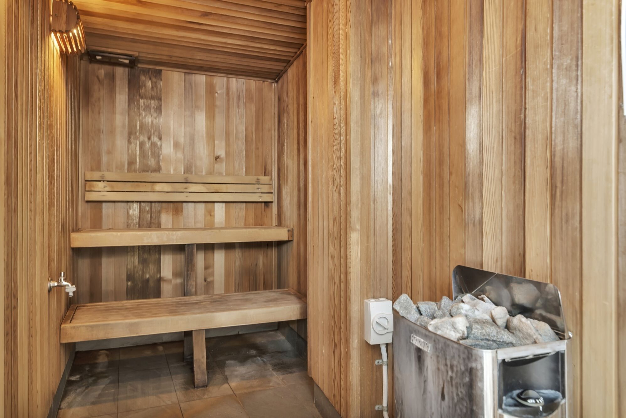 A wooden sauna with benches and a stone heater.