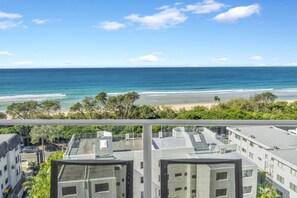 A view of the ocean from a balcony overlooking a beach, with buildings in the foreground. - Catalina Resort (Maroochydore)