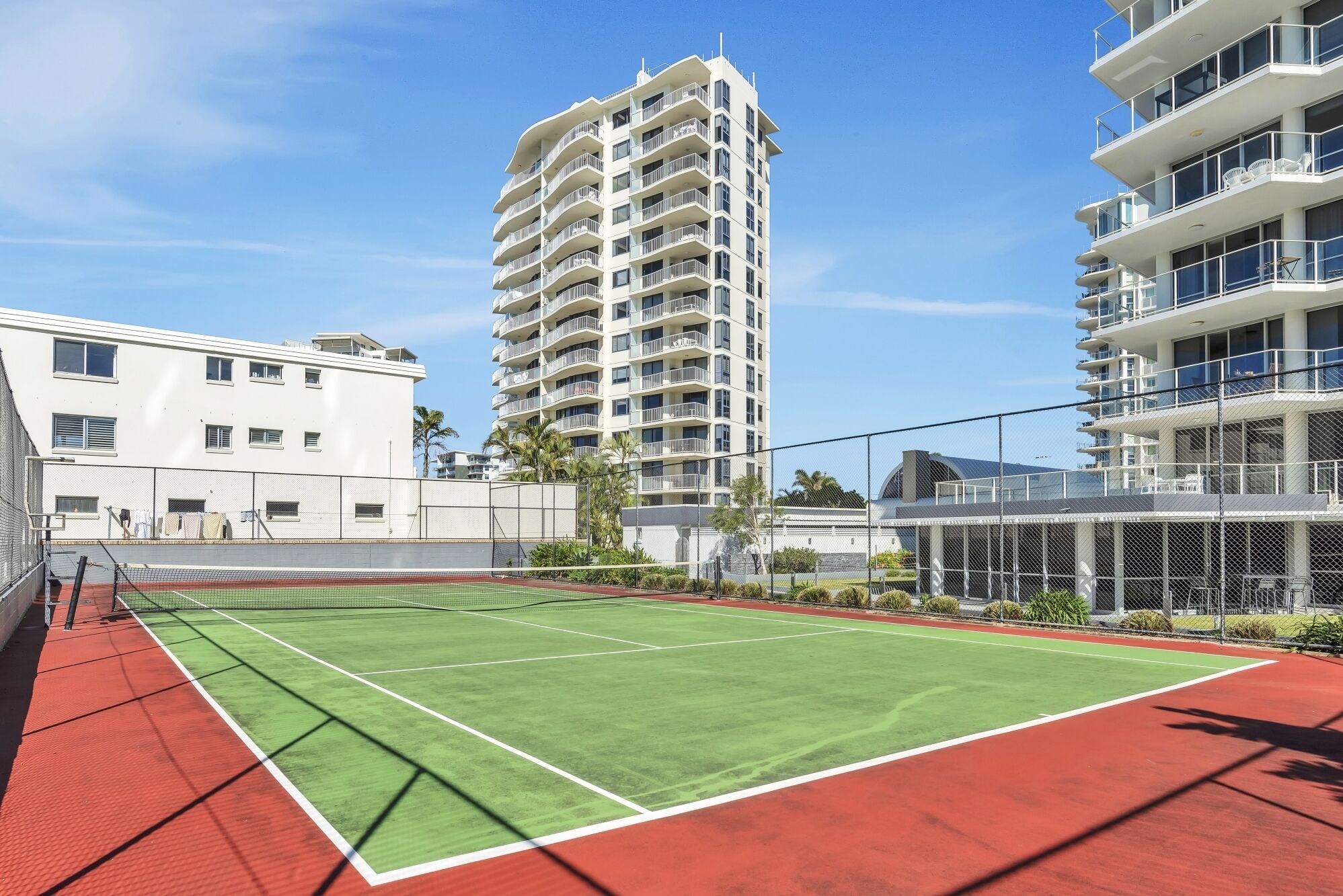 A tennis court surrounded by high-rise buildings.