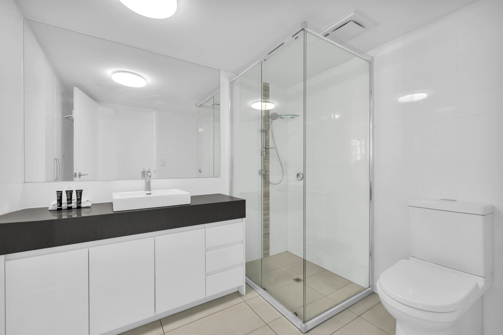 Un baño moderno con cabina de ducha de vidrio, lavabo blanco y inodoro.
