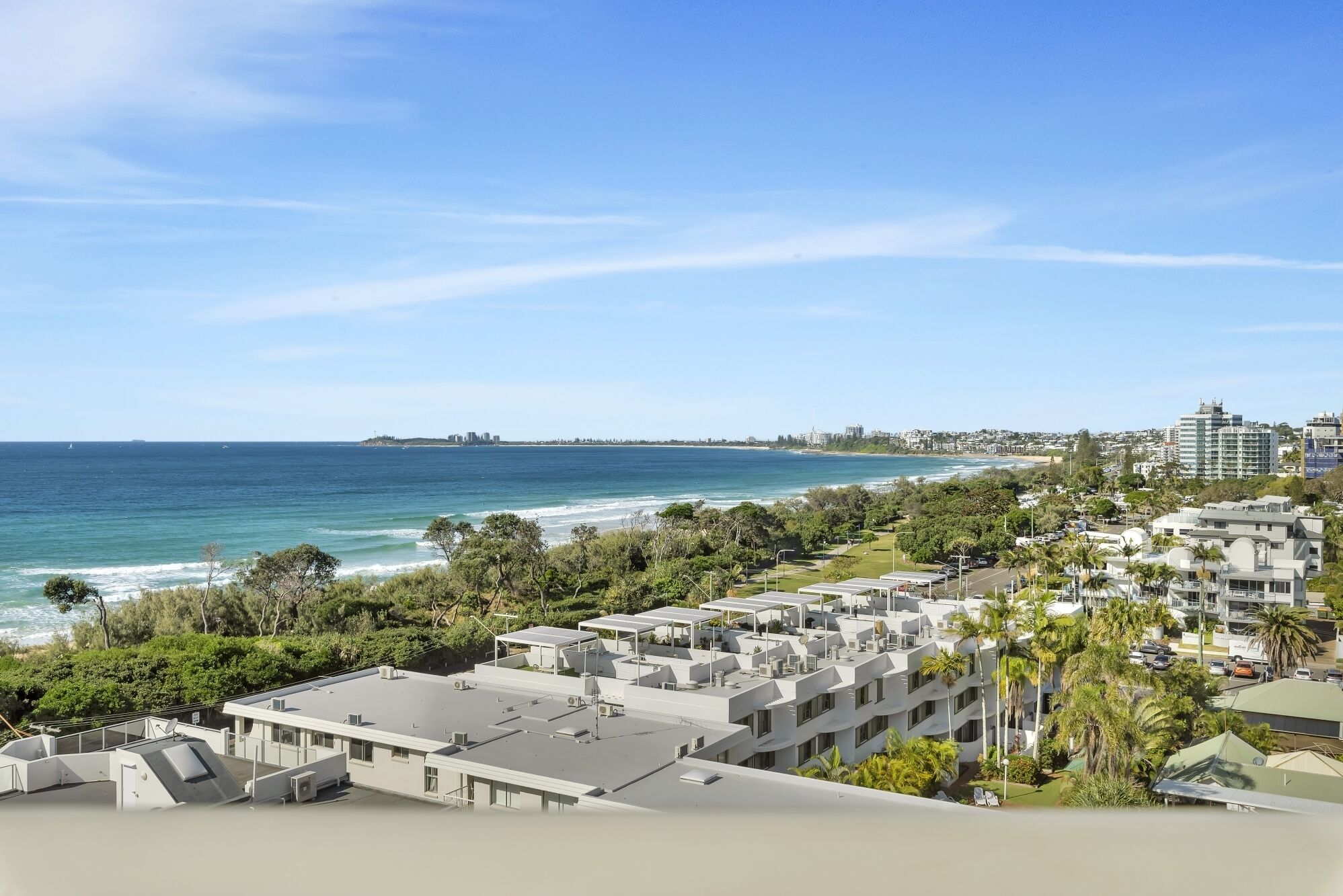 Un quartier résidentiel en bord de mer, avec des bâtiments modernes, une plage et un ciel dégagé.