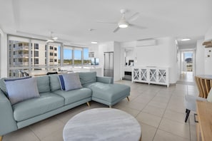A modern living room with a light blue sofa, a round coffee table, and a ceiling fan.