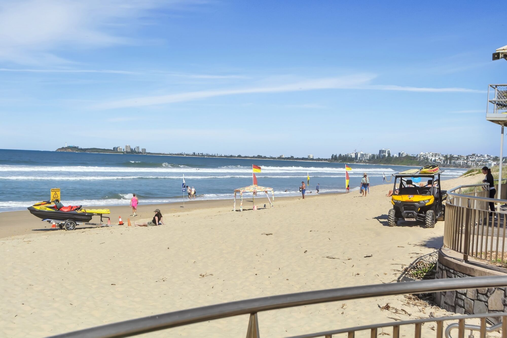 A beach with a jet ski, a lifeguard stand, and a dune buggy.