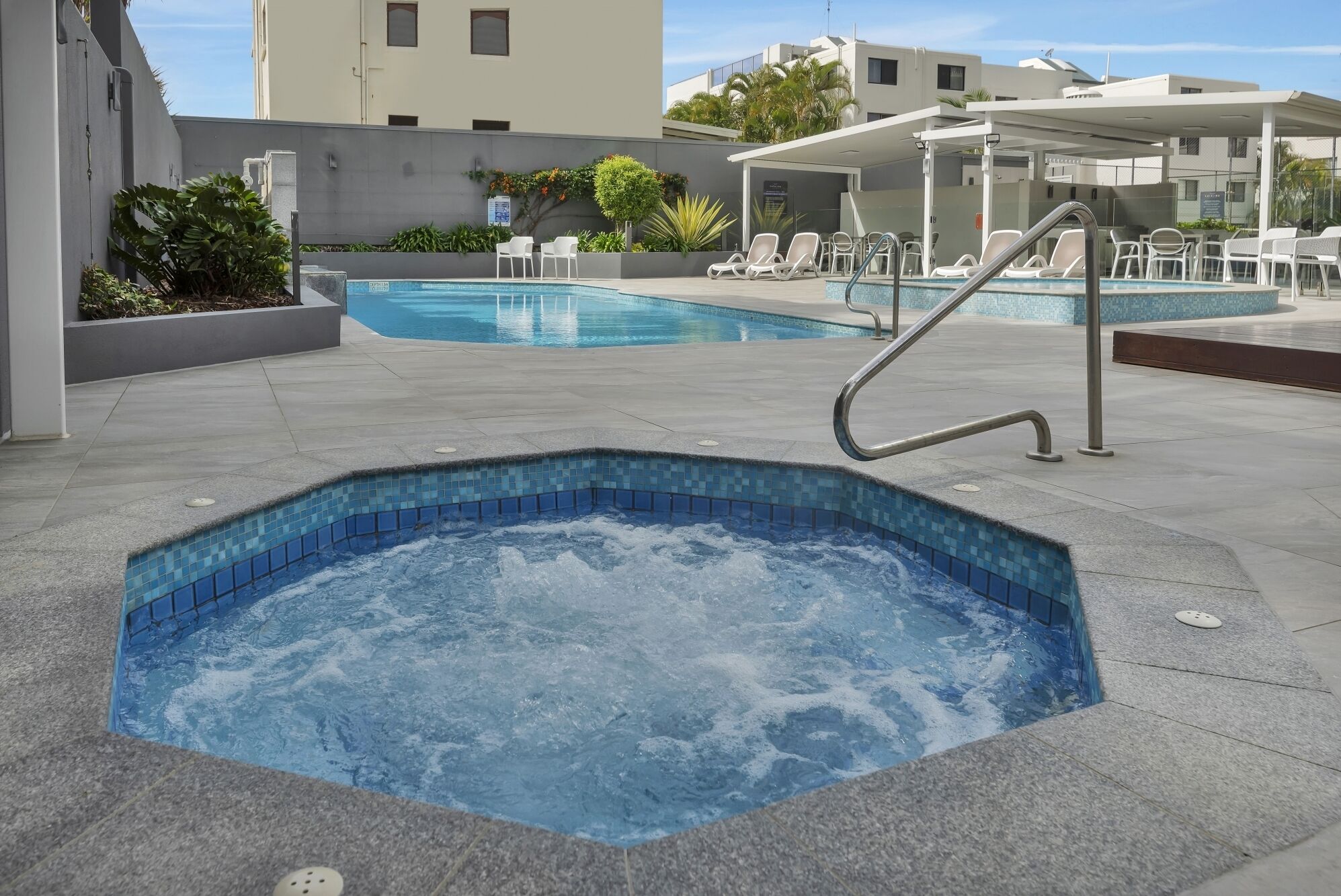 Un área de spa con jacuzzi, sillas de descanso y piscina.