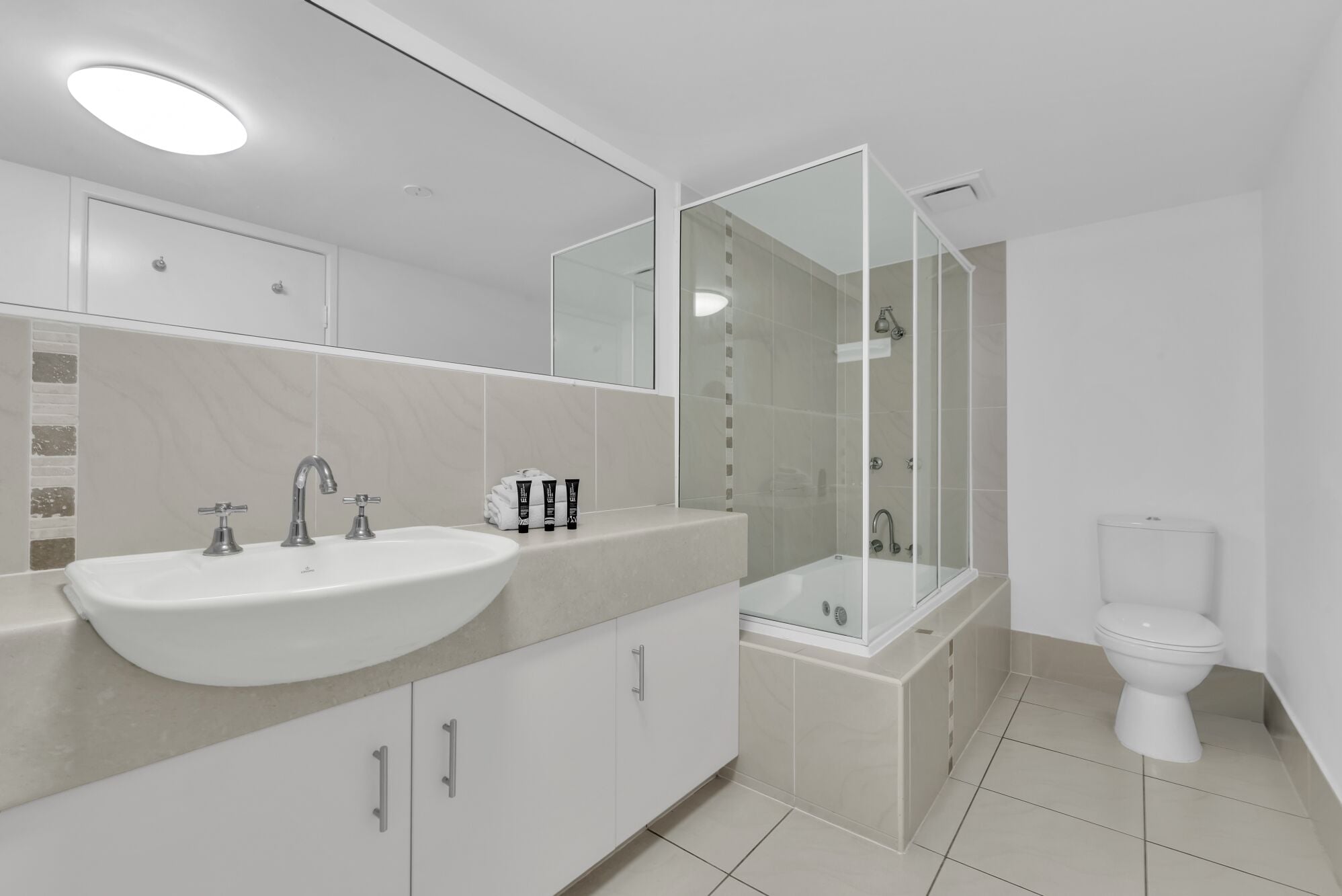 A modern bathroom with a large sink, a toilet, and a glass-enclosed shower.