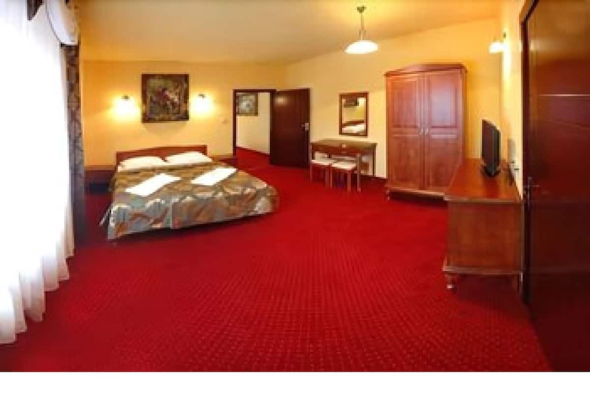 Quarto de hotel com cama, secretária, cadeira, guarda-roupa e um quadro na parede.
