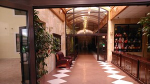 A hotel lobby with a checkered floor, leather seating, a plant, and a sports equipment display. - Dobosz (Police)