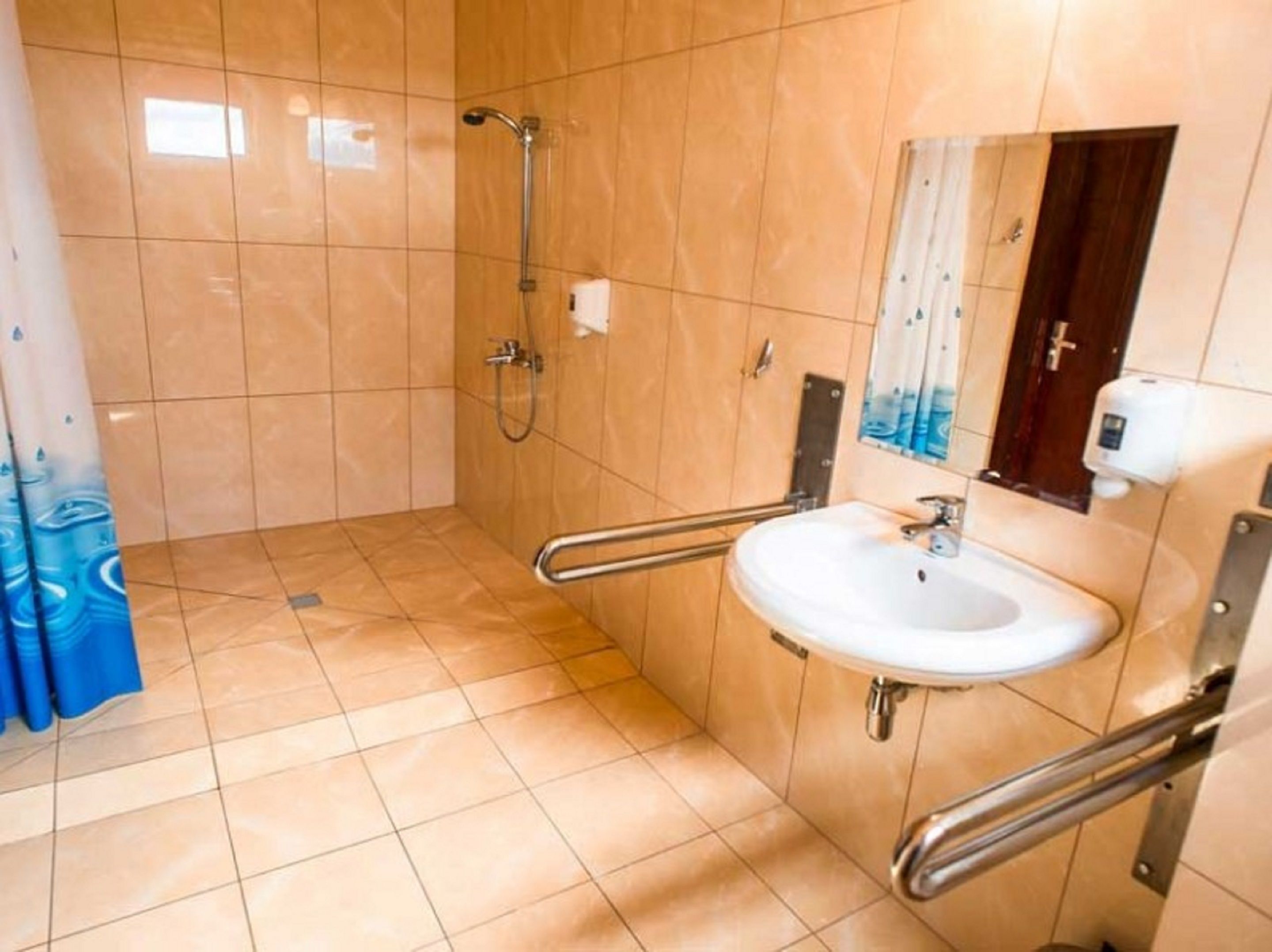 A bathroom with a shower, a sink, and a hand sanitizer dispenser.