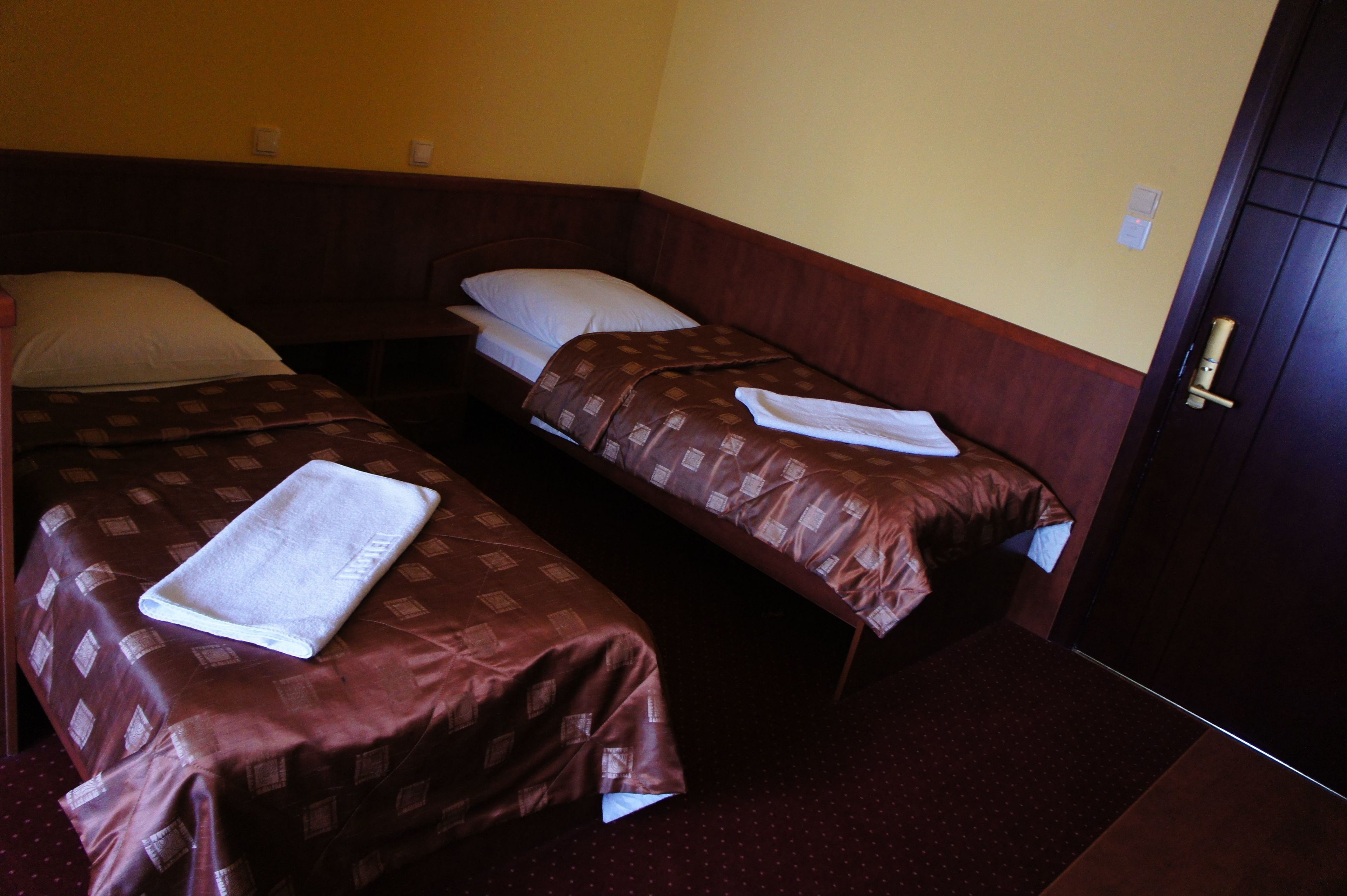 Habitació amb dos llits individuals, cadascun amb una col·cha marró i almoines blanques.