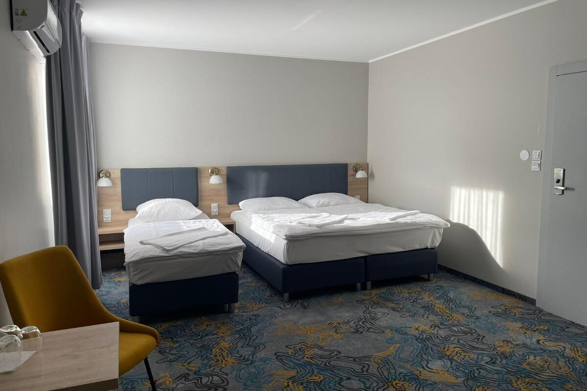 Habitación de hotel con dos camas, un escritorio, una silla y alfombra estampada.