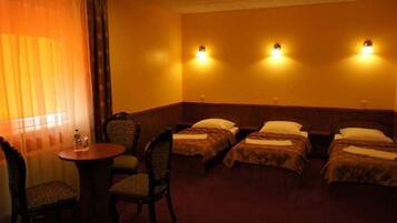 Une chambre d’hôtel avec deux lits, une petite table et deux chaises.