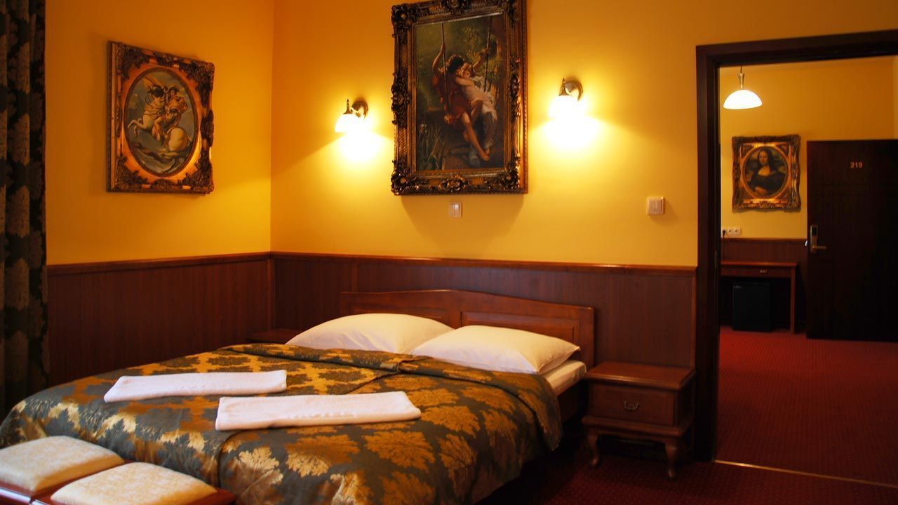 Una habitación de hotel con una cama grande, dos lámparas fijadas a la pared y una puerta con un número.