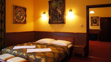 Una habitación de hotel con una cama grande, dos lámparas fijadas a la pared y una puerta con un número.