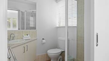 Ein Badezimmer mit Toilette, Waschbecken und Duschbereich.