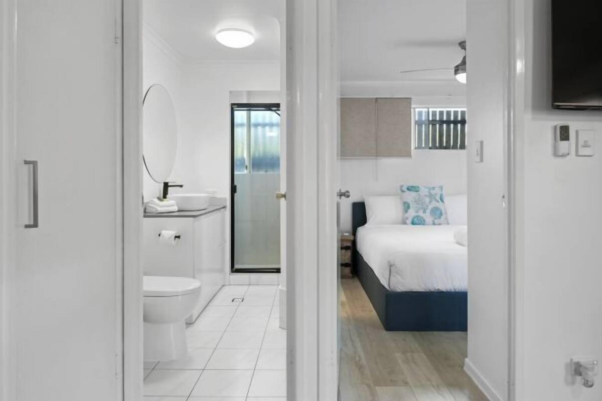 A modern hotel room with a bathroom, a bed, and a TV.