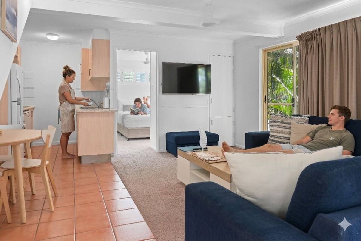 A modern apartment with a kitchen, dining area, living room, and a TV.