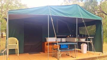 Una carpa verde con una mesa y sillas instaladas afuera.
