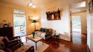 A cozy living room with wooden floors, a sofa, a coffee table, and a lamp. - Mt Barney Lodge Country Retreat (Mount Barney)