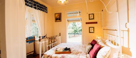 A bedroom with a bed, a window, a chandelier, and a balcony.