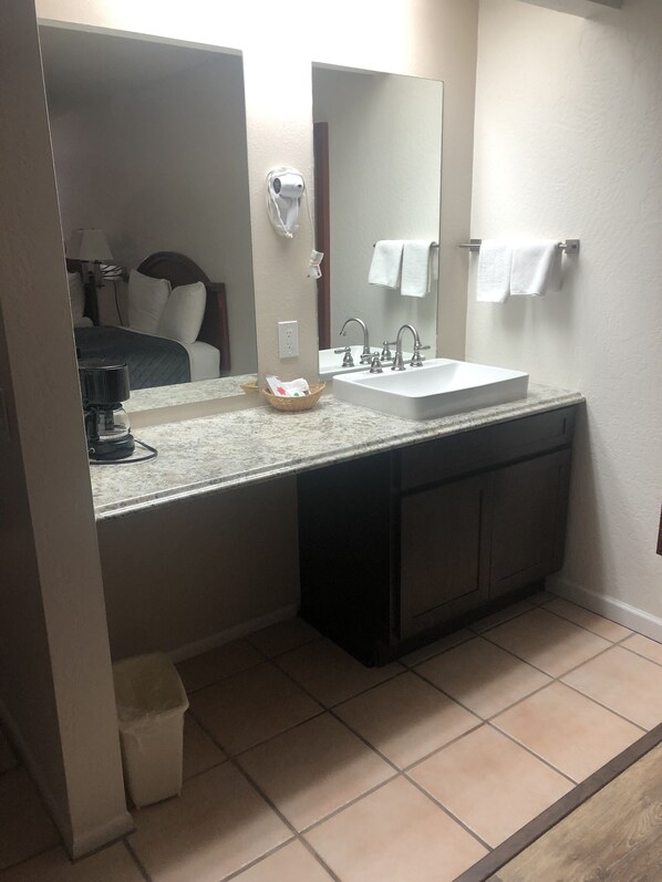 Une salle de bain avec un double lavabo, un miroir, un porte-serviettes et une poubelle.