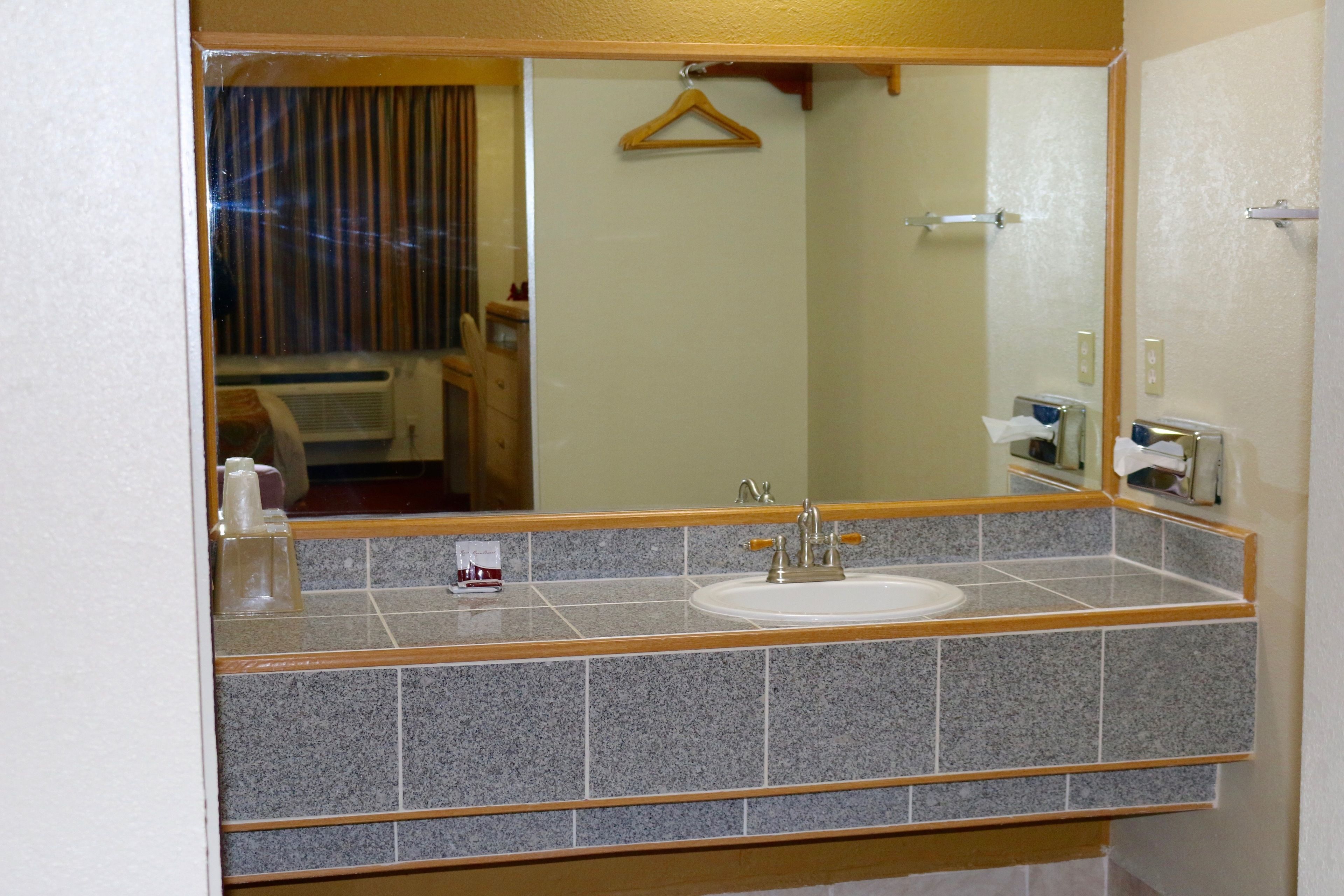 Ein Badezimmer mit Granitplatte, einem weißen Waschbecken und einem Spiegel.