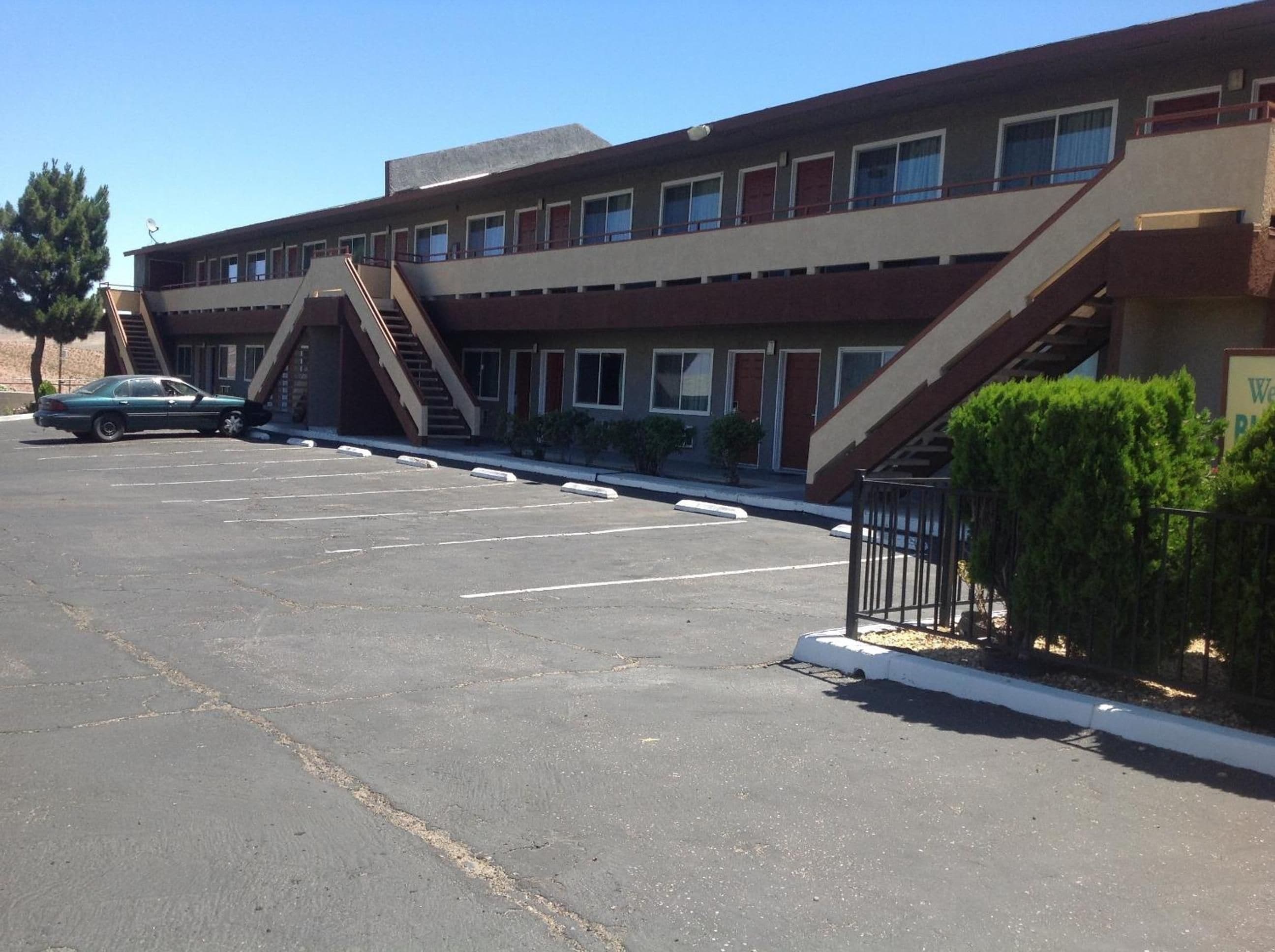 Un edificio de varios pisos con estacionamiento, una escalera y un cartel que indica uso comercial u oficina.