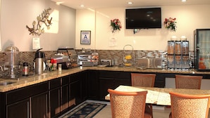 A modern kitchen with granite countertops, dark cabinetry, and a breakfast bar. - Budget Inn Barstow (Barstow)