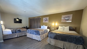 A hotel room with three beds, a flat-screen TV, and two wall-mounted lamps. - Budget Inn Barstow (Barstow)