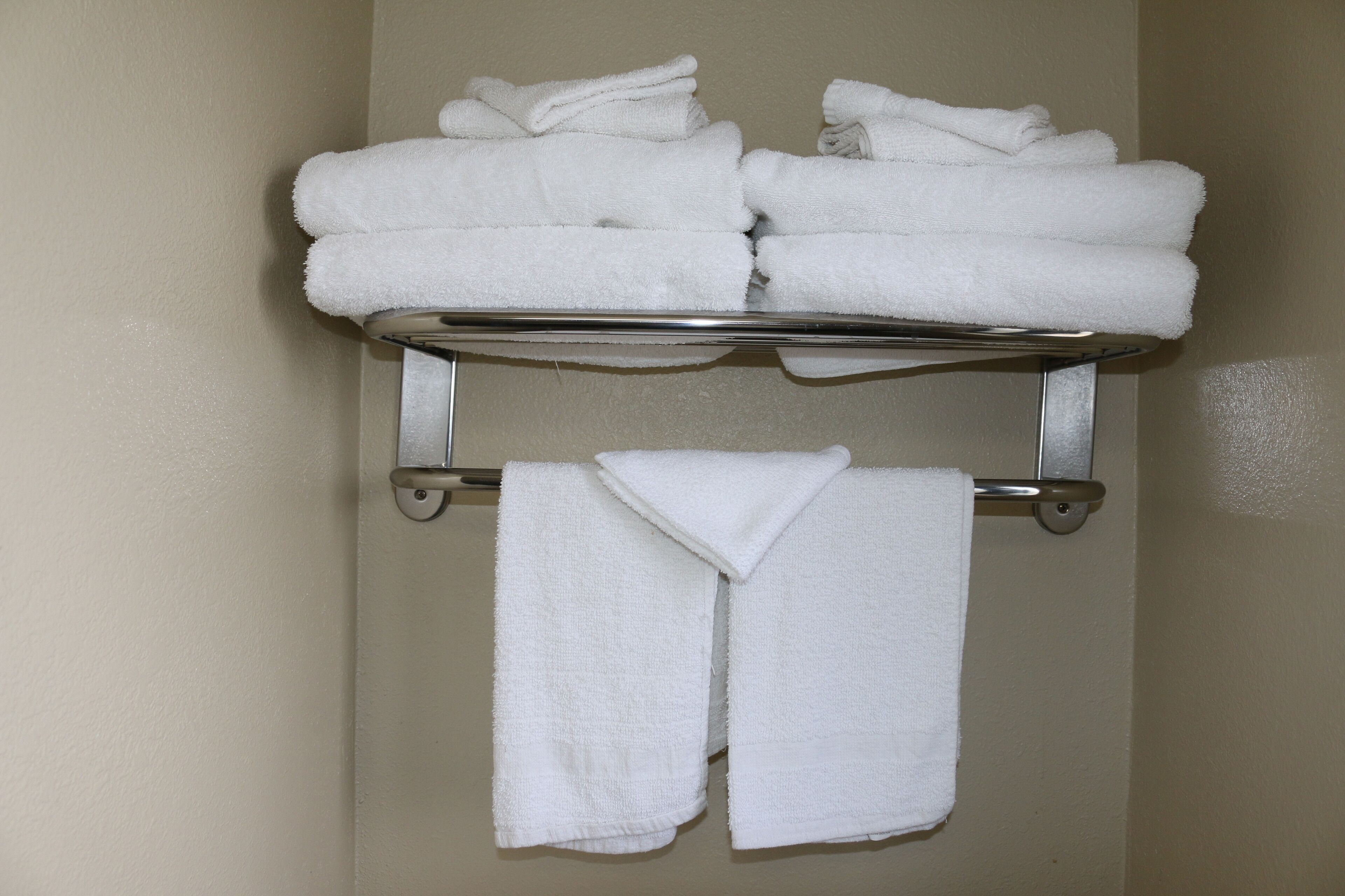 A bathroom with a towel rack holding folded towels.