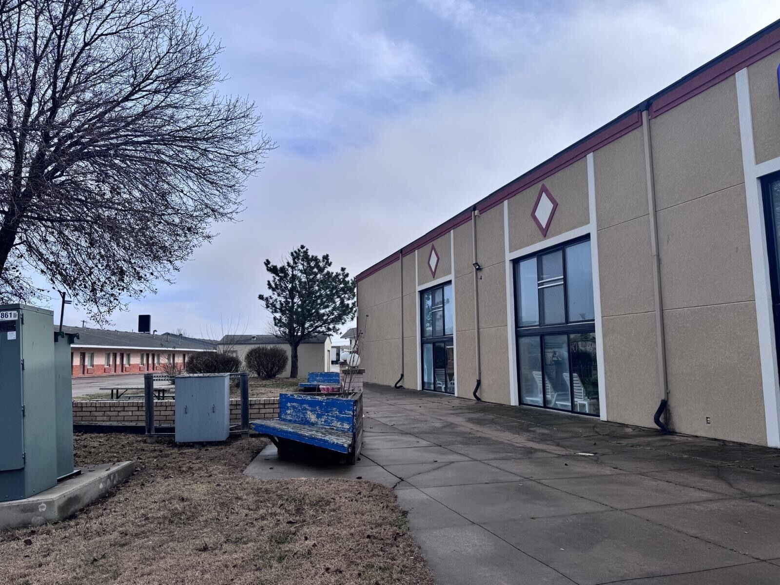 A building with a large window, a bench, and a tree in front.
